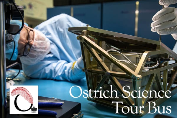 A scientist in a clean room suit leans on a bench top to adjust a spacecraft radiator.