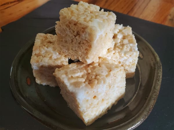 A small ceramic plate, piled with tempting rice krispy treat cubes.